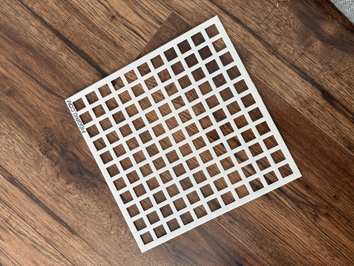 Szablon FigGrid 25×25 cm — biała siatka 11×11 z napisem FIGGRID.COM, na drewnianym tle